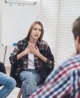 Vertrauen, Austausch und emotionale Offenheit in der Gruppe Junge Frau spricht offen in einer Gruppentherapie oder Gesprächsrunde